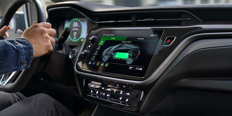  Driver operating an electric vehicle with touchscreen dashboard displaying energy usage and battery status.