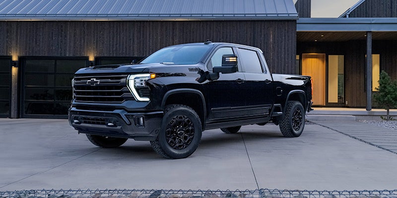 Black Chevrolet Silverado HD pickup truck parked in front of a modern