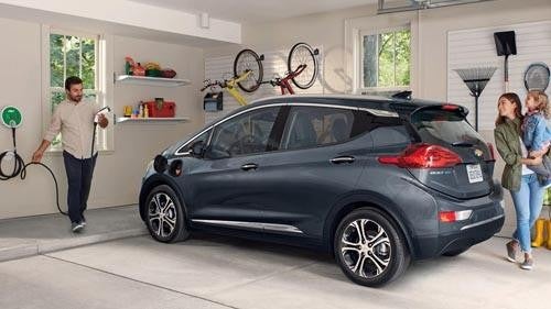 Woman plugging in electric vehicle at a charging station